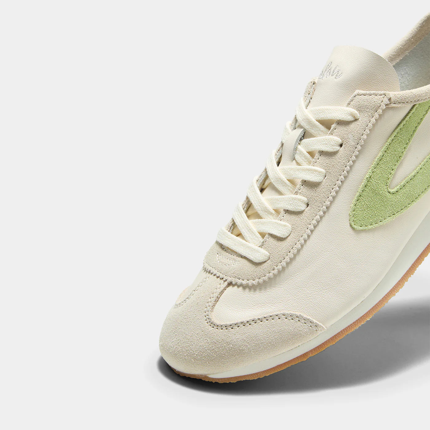 Close-up view of the Norman Walsh sneaker in Beige and Grass Green, featuring premium full-grain leather and suede textures with a durable rubber sole.