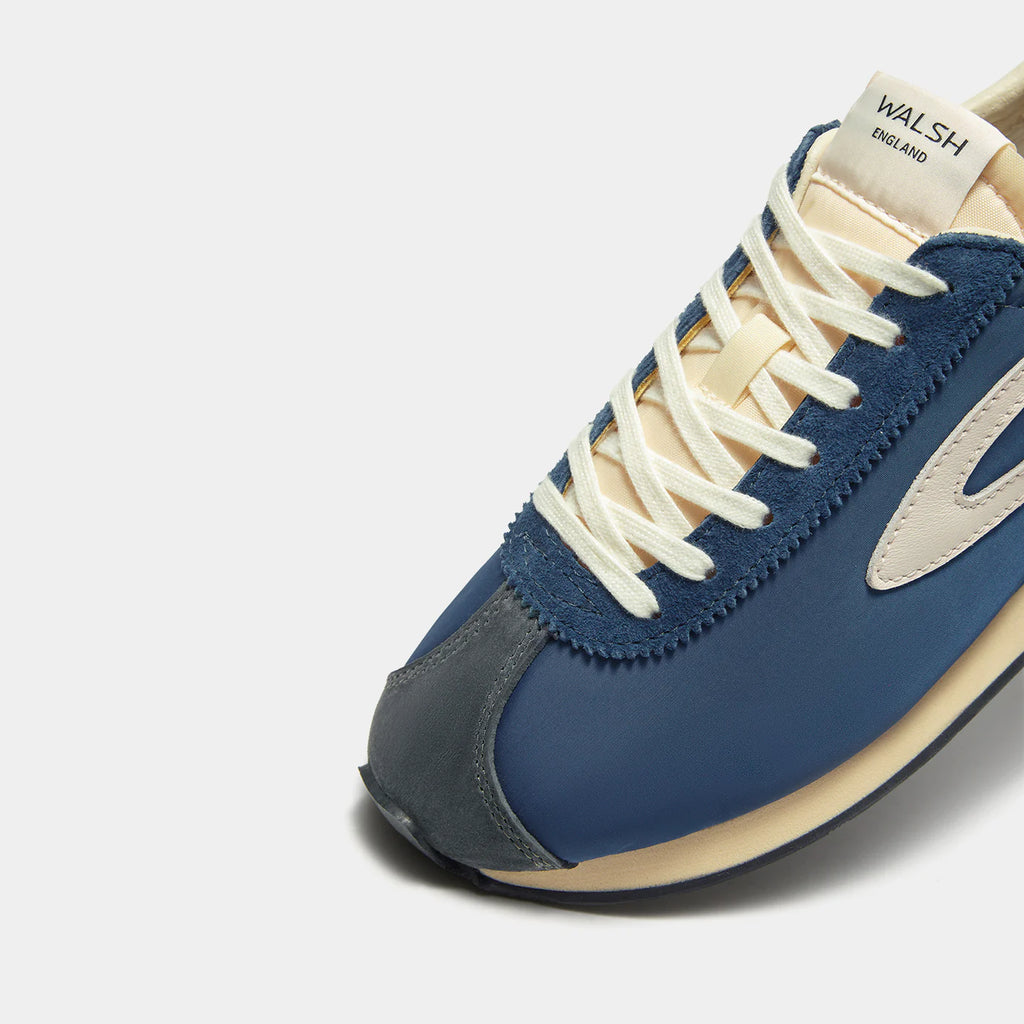 Close-up view of the London Navy Blue sneaker, showing the refined 1970s Scintilla silhouette and weather-resistant material textures.